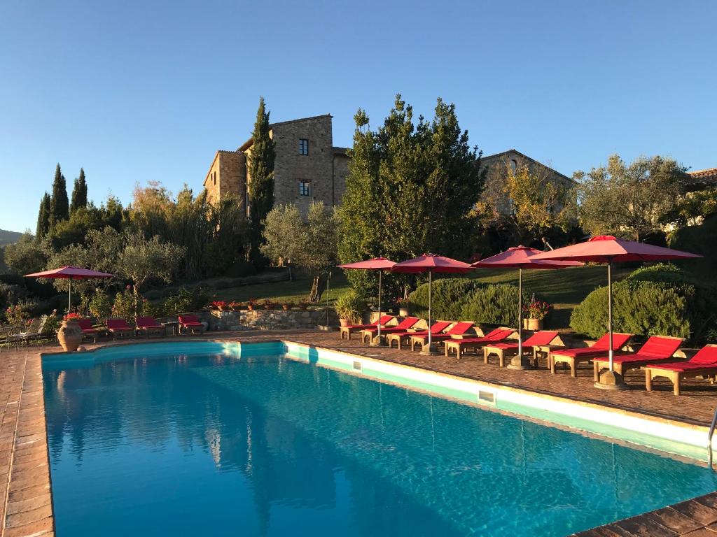 a swimming pool with red chairs and umbrellas at Tenuta Di Canonica in Todi