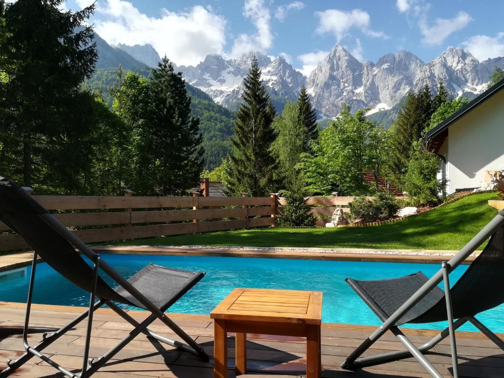 een paar stoelen en een tafel naast een zwembad bij Hiša Katja-Privat wellness in Kranjska Gora