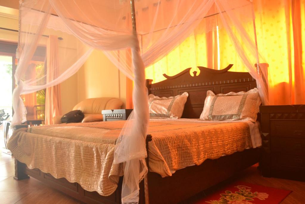 um quarto com uma cama de dossel grande em The Palms Beach Hotel em Entebbe