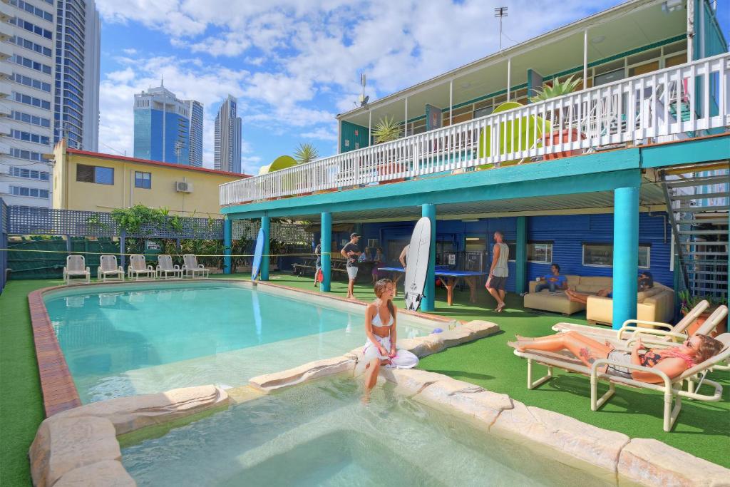 Eine Frau, die in einem Schwimmbad in einem Hotel sitzt. in der Unterkunft Backpackers In Paradise 18-35 Hostel in Gold Coast