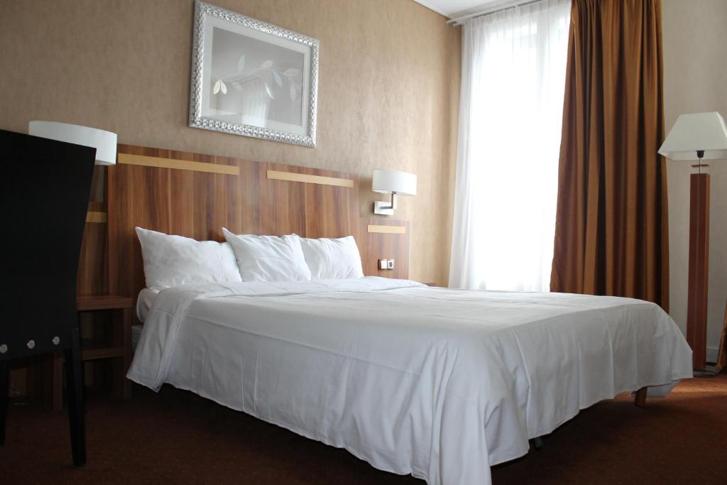 uma cama num quarto de hotel com uma colcha branca em Hotel The Originals du Grand Monarque Nantes Gare em Nantes