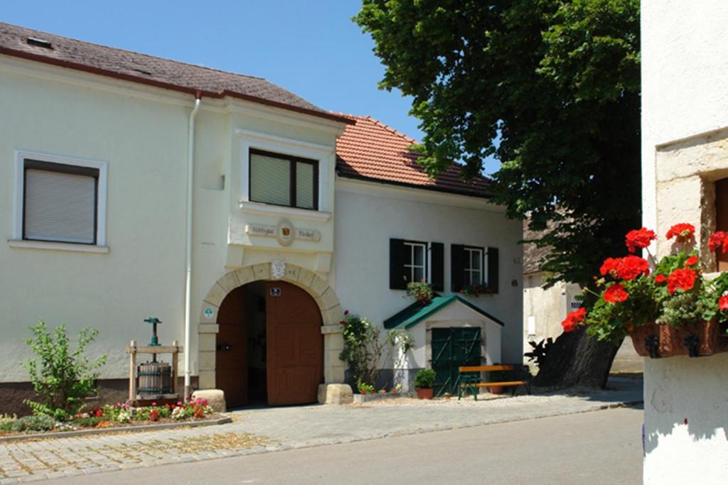 ein weißes Gebäude mit brauner Tür und roten Blumen in der Unterkunft Winzerzimmer - Weingut Tinhof in Eisenstadt