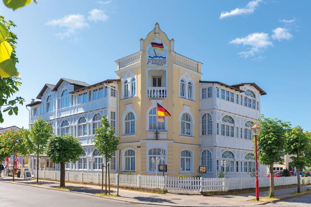 un bâtiment jaune et blanc avec une clôture blanche dans l'établissement Hotel Deutsche Flagge, à Binz