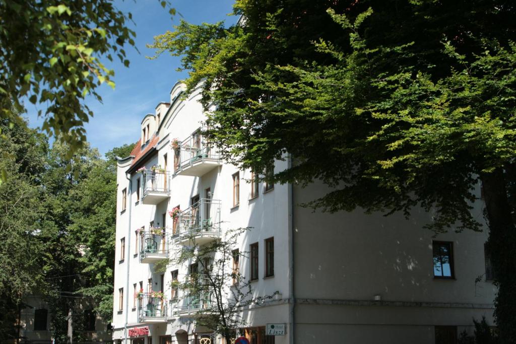 - un bâtiment blanc avec balcon dans une rue dans l'établissement Hotel Liszt, à Weimar