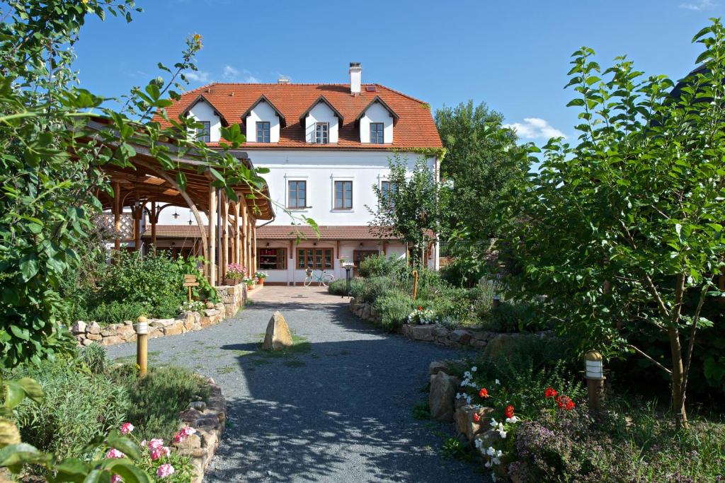 a large white house with a pathway in a garden at Babiččina Zahrada Penzion & Restaurant in Pruhonice