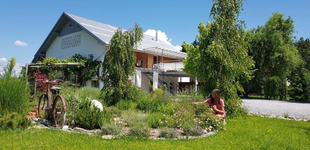 uma mulher sentada num jardim em frente a uma casa em Hillside Bio Resort Delux Apartments em Šešče pri Preboldu