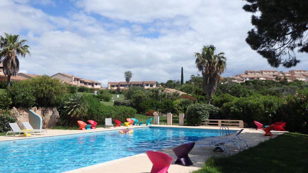 een zwembad met stoelen en een resort bij Résidence les Hameaux de Bocca del Oro in Porto-Vecchio