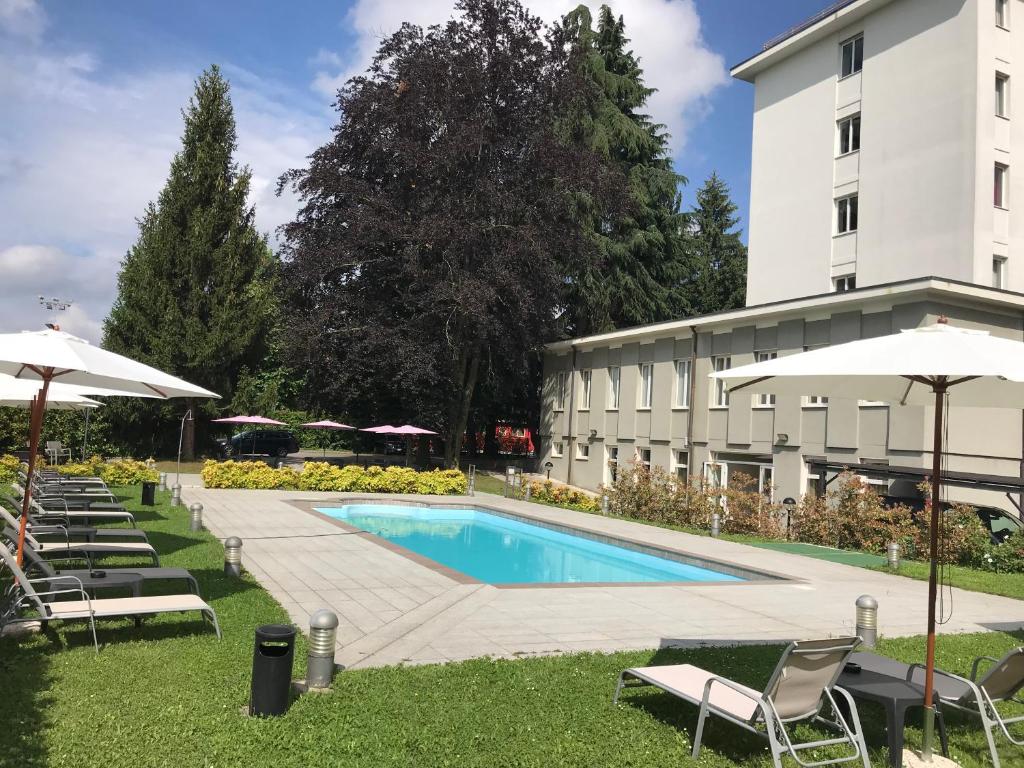 una piscina frente a un edificio con sillas y sombrillas en Bis Hotel Varese, en Varese