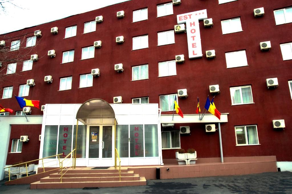 un hôtel rouge avec des drapeaux à l'avant dans l'établissement Hotel Est, à Bucarest