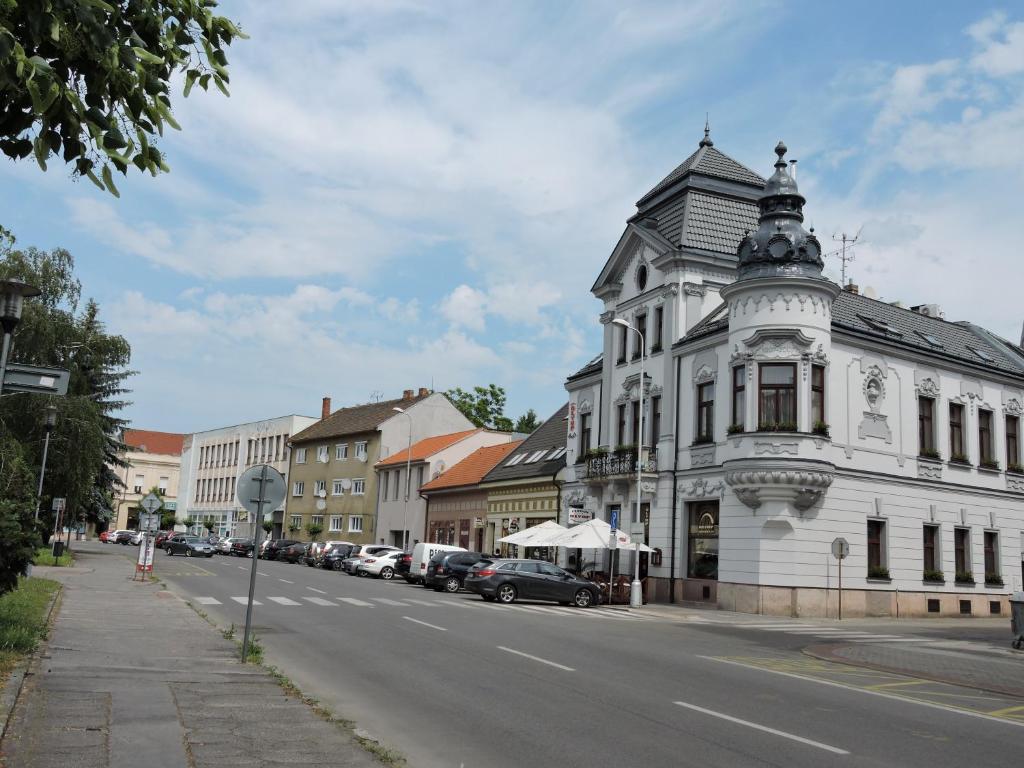 a white building with a turret on a city street at Olymp penzion in Komárno