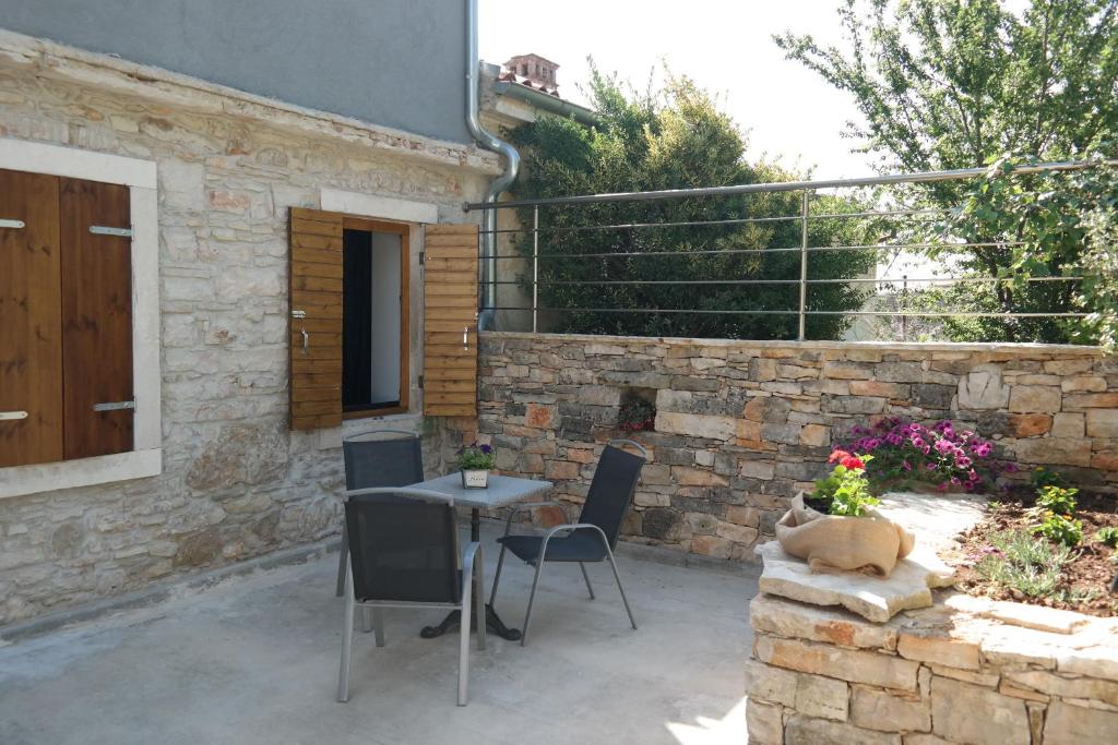 un patio con mesa, sillas y pared de piedra. en Apartments Hedona, en Pula