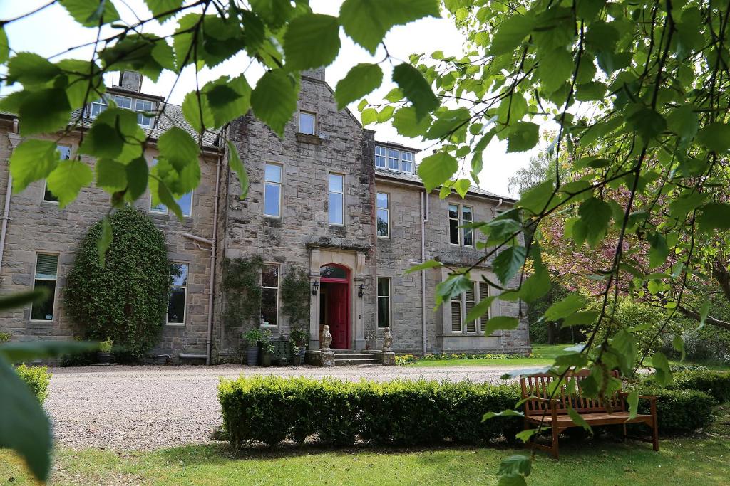 une ancienne maison en pierre avec une porte rouge dans l'établissement Carnach House, à Nairn