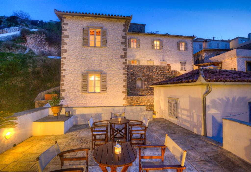 un patio avec des tables et des chaises en face d'un bâtiment dans l'établissement Nereids Guesthouse, à Hydra