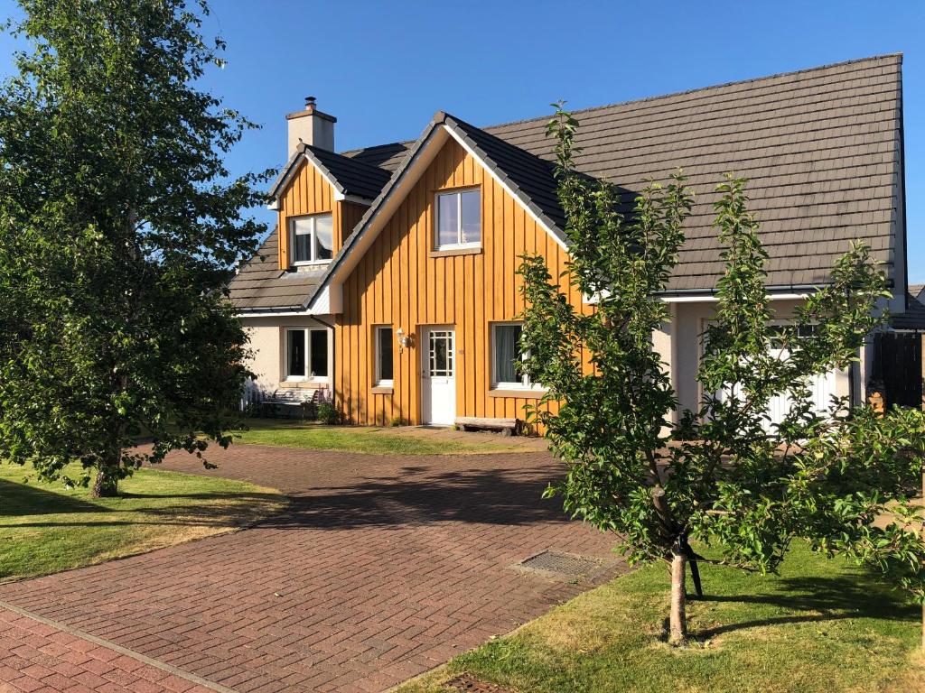 een geel huis met een gambrel dak bij Hector's House in Aviemore