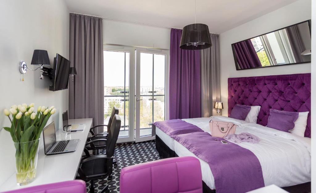 Cette chambre d'hôtel comprend un lit violet et un bureau. dans l'établissement Apartamenty Vola Residence, à Varsovie