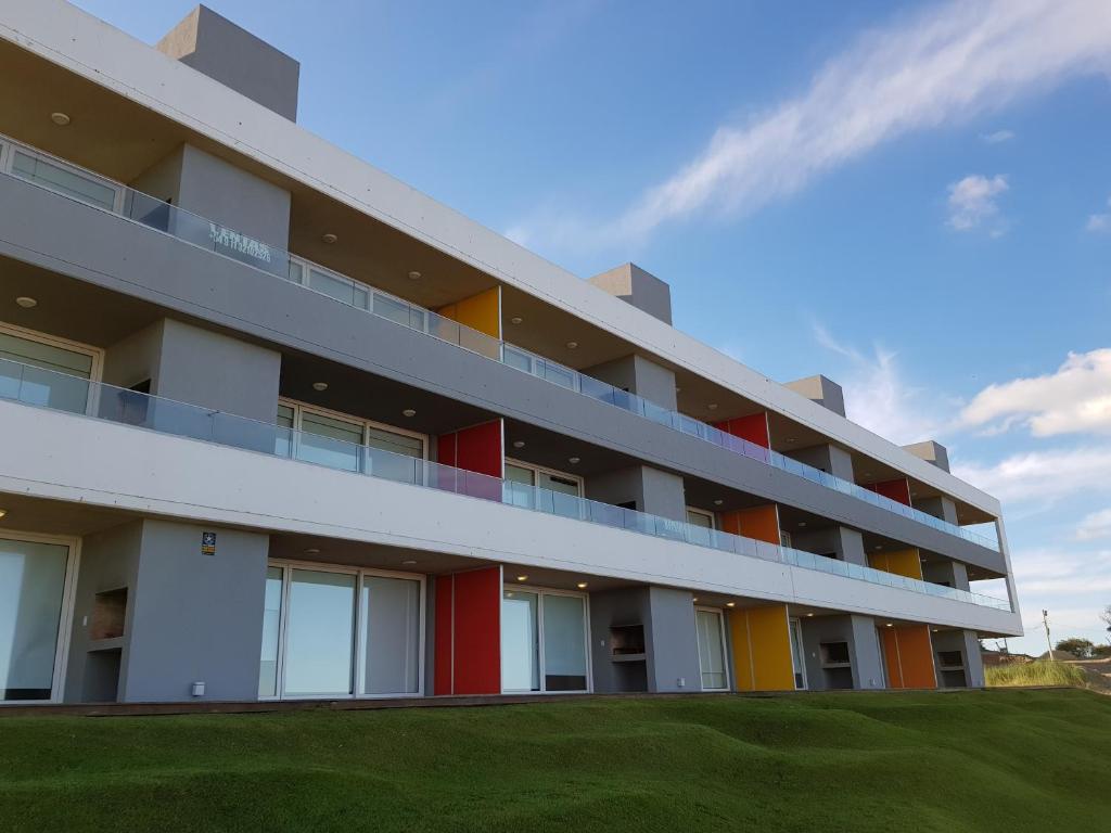 un edificio bianco con finestre colorate e un campo verde di Meca Playa a Villa Gesell