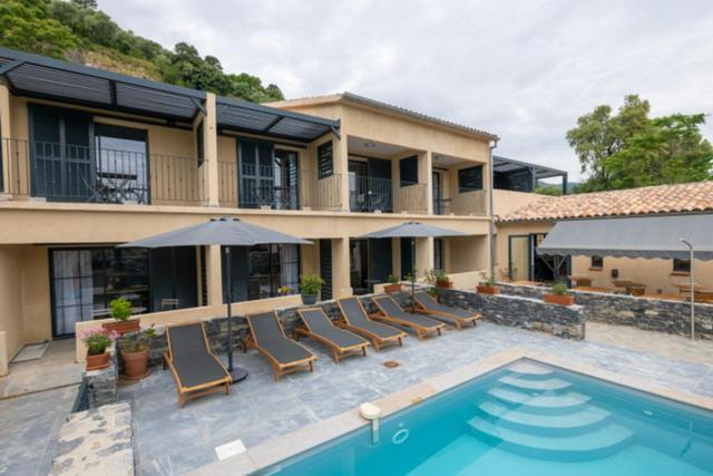 une maison dotée d'une piscine avec des chaises et un parasol dans l'établissement Casa di a Restonica, à Corte