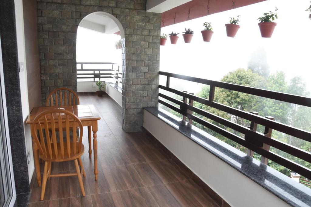 een balkon met een tafel en stoelen in een kamer bij Nirvana Retreat in Kurseong