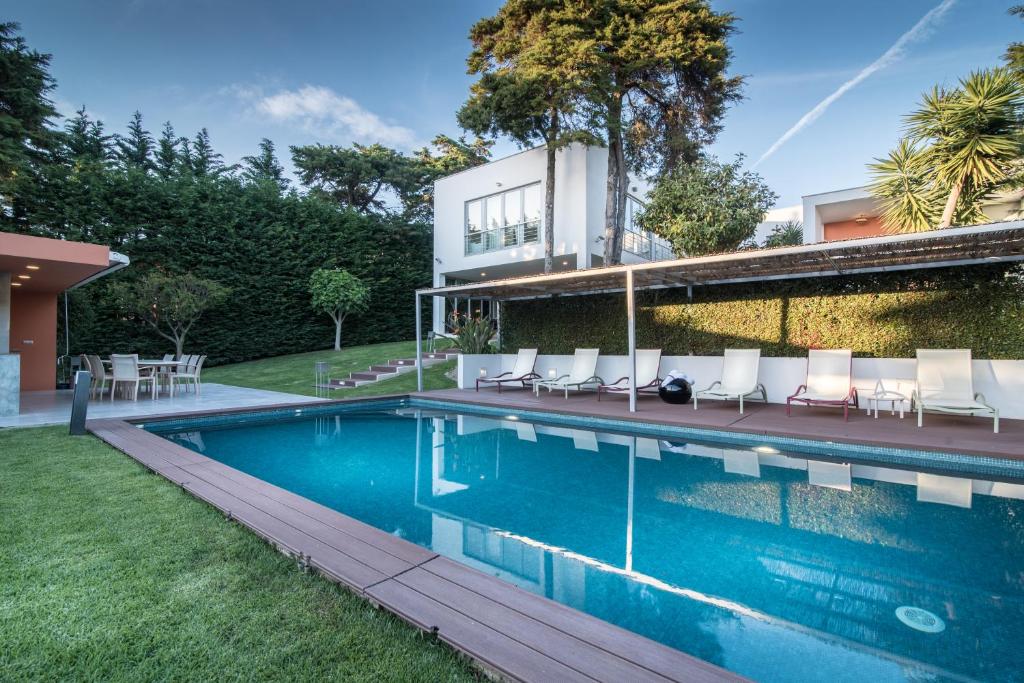 een huis met een zwembad met stoelen en een gebouw bij Cascais Casa Laranja in Cascais