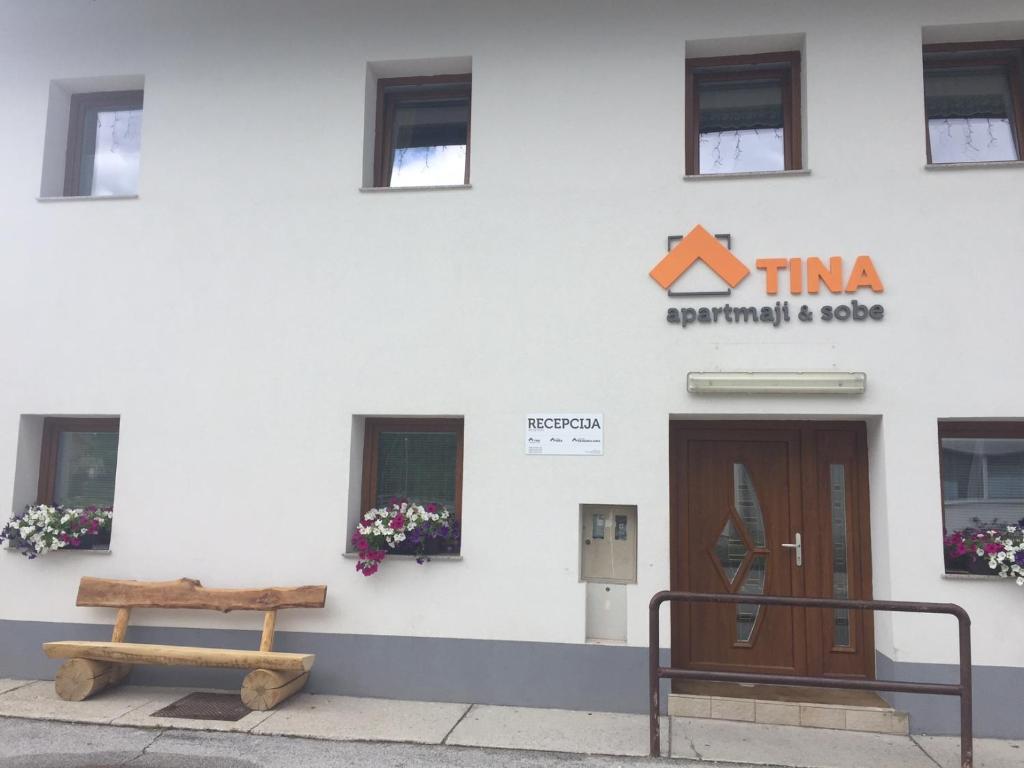 een gebouw met een deur en een bank ervoor bij Apartmaji in sobe Tina in Kranjska Gora