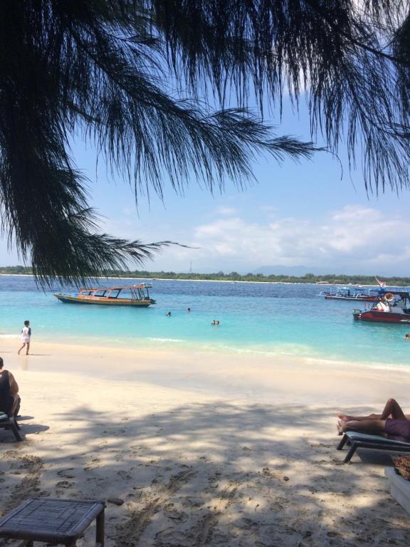 una playa con barcos y gente en el agua en Gili Turtle Beach Resort, en Gili Trawangan