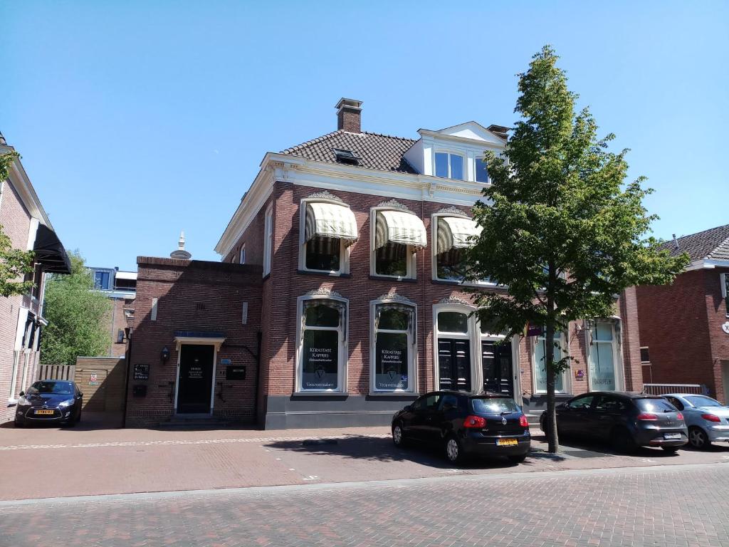 een gebouw van rode baksteen met auto's voor de deur bij B&B de Notaris in Assen