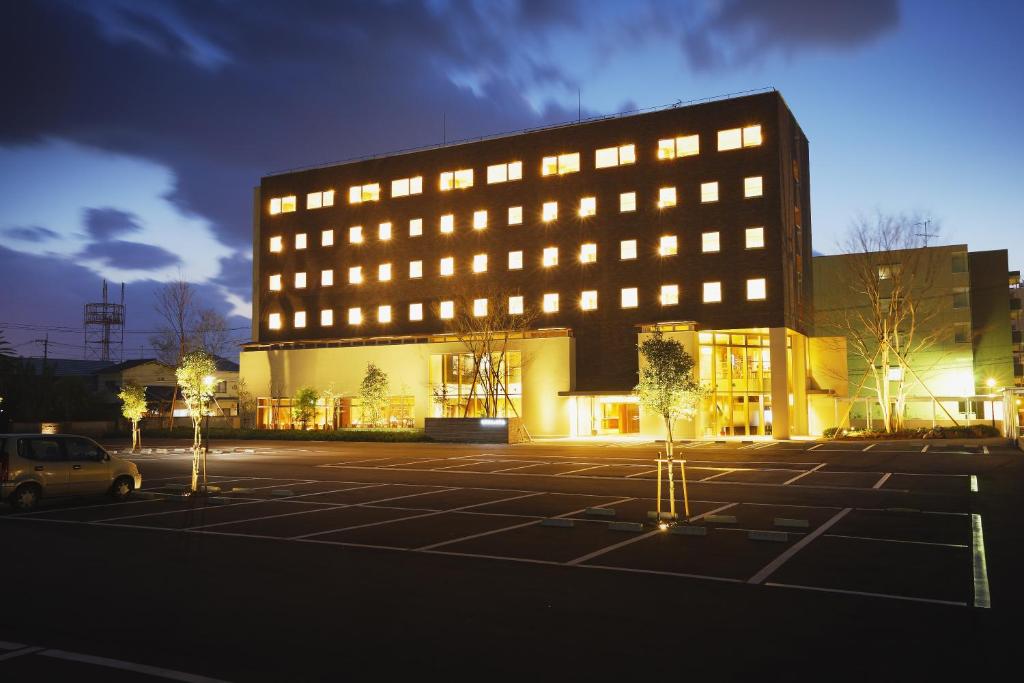 un grande edificio con luci in un parcheggio di Takanokono Hotel a Matsuyama