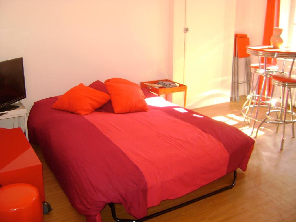 1 cama con almohadas de color naranja en una habitación en le corsaire, en Granville