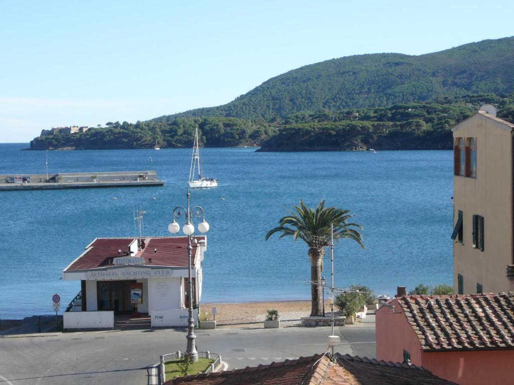 a view of a beach with a building and a palm tree at Affittacamere Vista Mare in Porto Azzurro