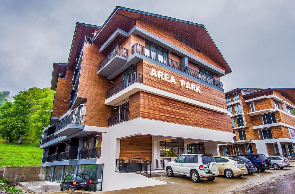 un immeuble d'appartements avec des voitures garées devant lui dans l'établissement Area Park Bakuriani, à Bakuriani