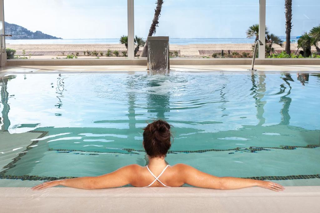 Eine Frau, die in einem Pool mit Meerblick liegt. in der Unterkunft Hotel Montecarlo Spa & Wellness in Roses