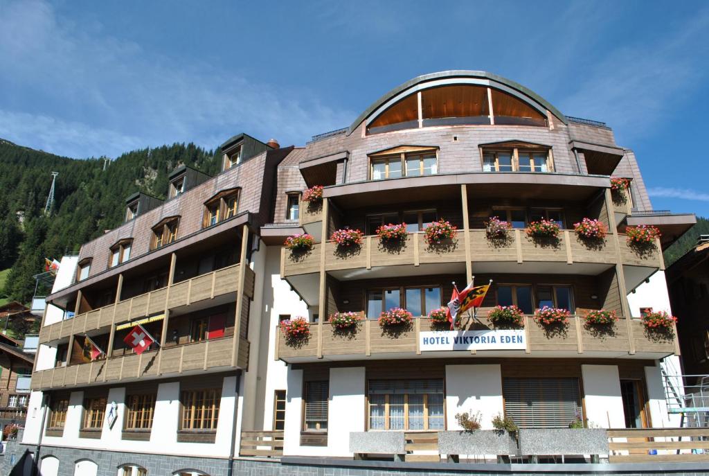 ein Gebäude mit Blumen auf den Balkonen in der Unterkunft Hotel Viktoria Eden in Adelboden