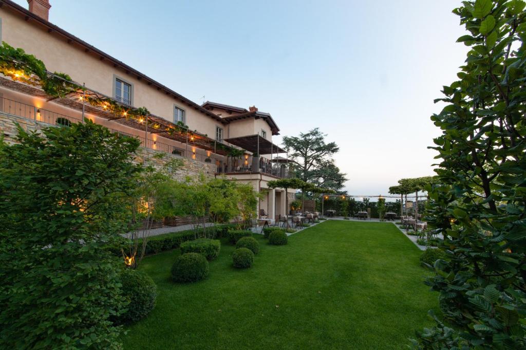 einen großen Innenhof mit grünem Rasen und einem Gebäude in der Unterkunft Relais San Vigilio al Castello in Bergamo