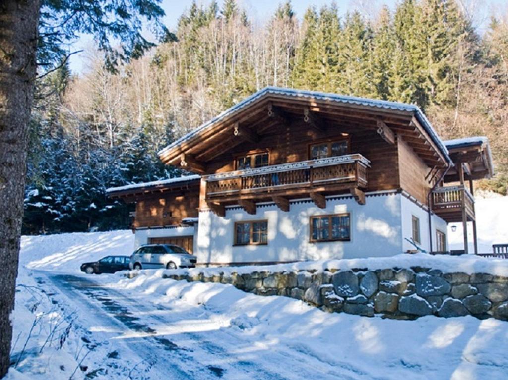 une cabane en rondins dans la neige avec une voiture garée devant dans l'établissement Ferienwohnung Steiner, à Wald im Pinzgau