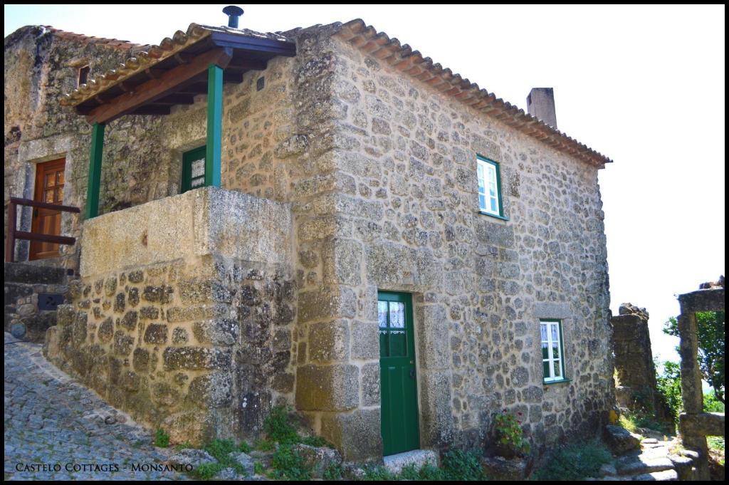 um antigo edifício de pedra com uma porta verde em Castelo Cottages II em Monsanto