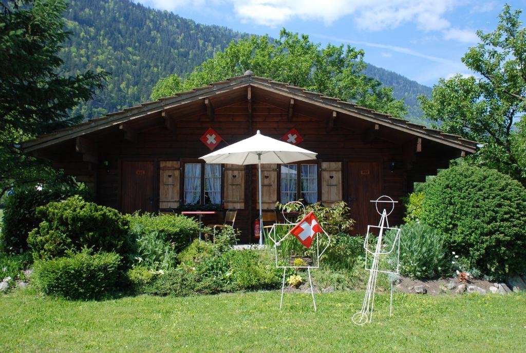 una baita di tronchi con ombrellone e sedie di fronte ad essa di Salzano Basic Rooms Interlaken a Interlaken