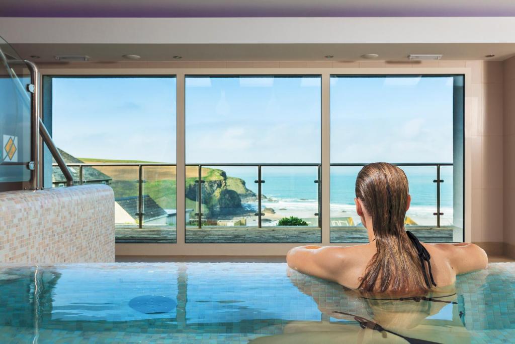 een vrouw in een zwembad met uitzicht op de oceaan bij Bedruthan Hotel & Spa in Newquay