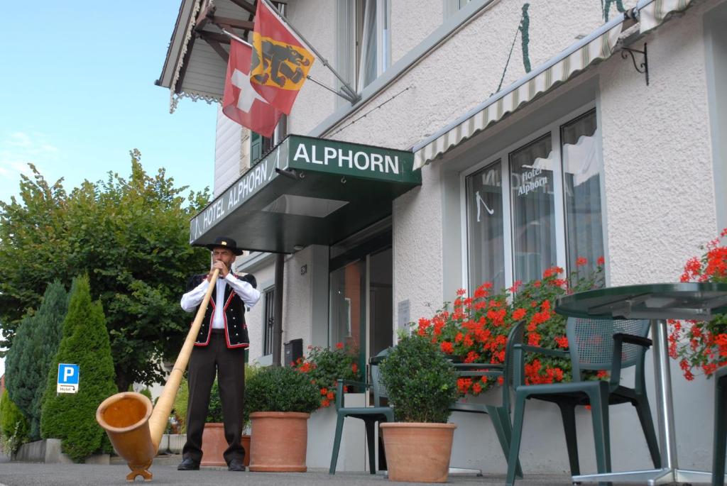 un homme tenant une batte de baseball devant un magasin dans l'établissement Hotel Alphorn, à Interlaken