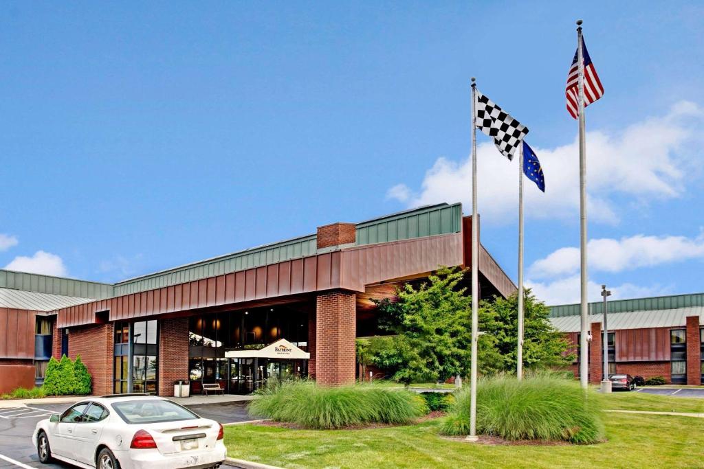 une voiture garée devant un bâtiment arborant un drapeau américain dans l'établissement Baymont by Wyndham Indianapolis West, à Indianapolis