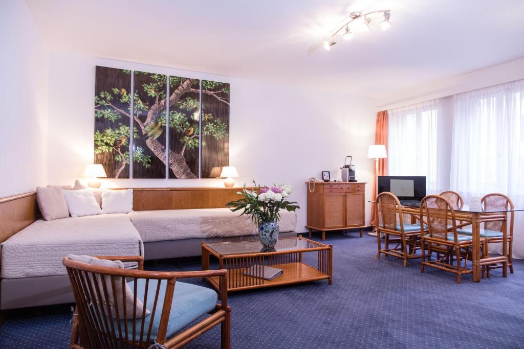 a living room with a couch and a table and chairs at Hotel Sagitta in Geneva