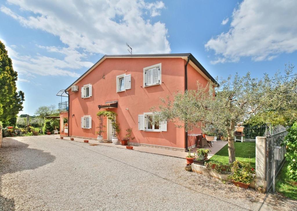 een rood huis met een hek en een oprit bij Lorena Apartments in Umag