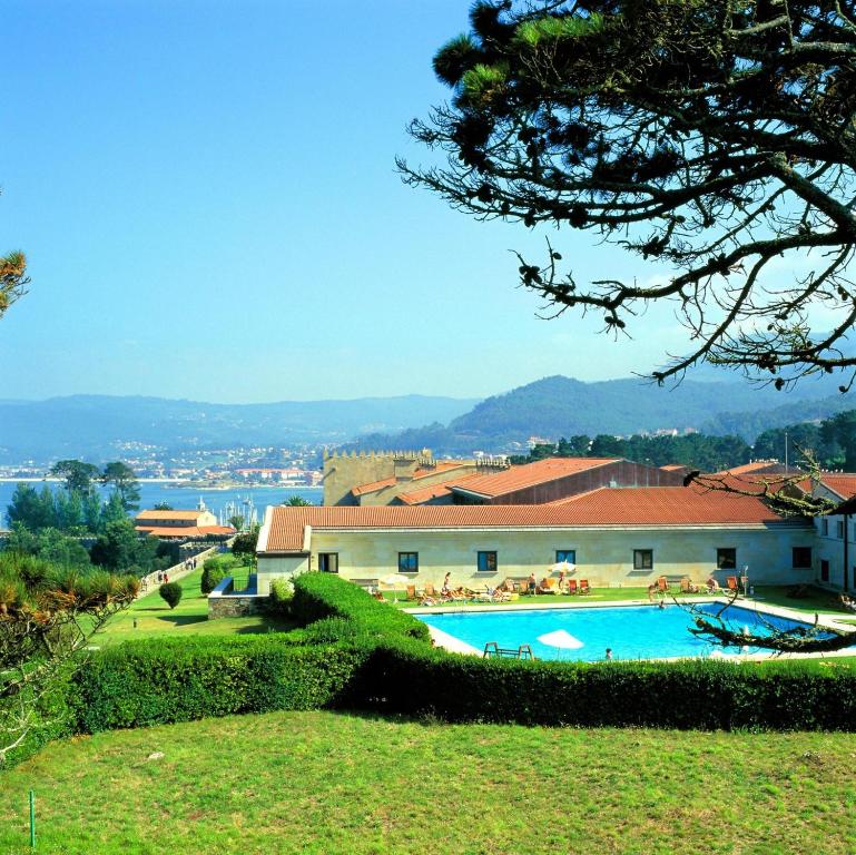 un complexe avec une piscine et un bâtiment dans l'établissement Parador de Baiona, à Baiona