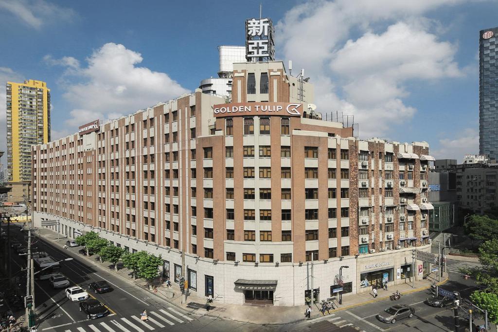 ein großes Gebäude mit einem Schild darüber in der Unterkunft Golden Tulip Bund New Asia (The Former Jinjiang Metropolo Hotel Classiq Shanghai,Rock Bund) in Shanghai