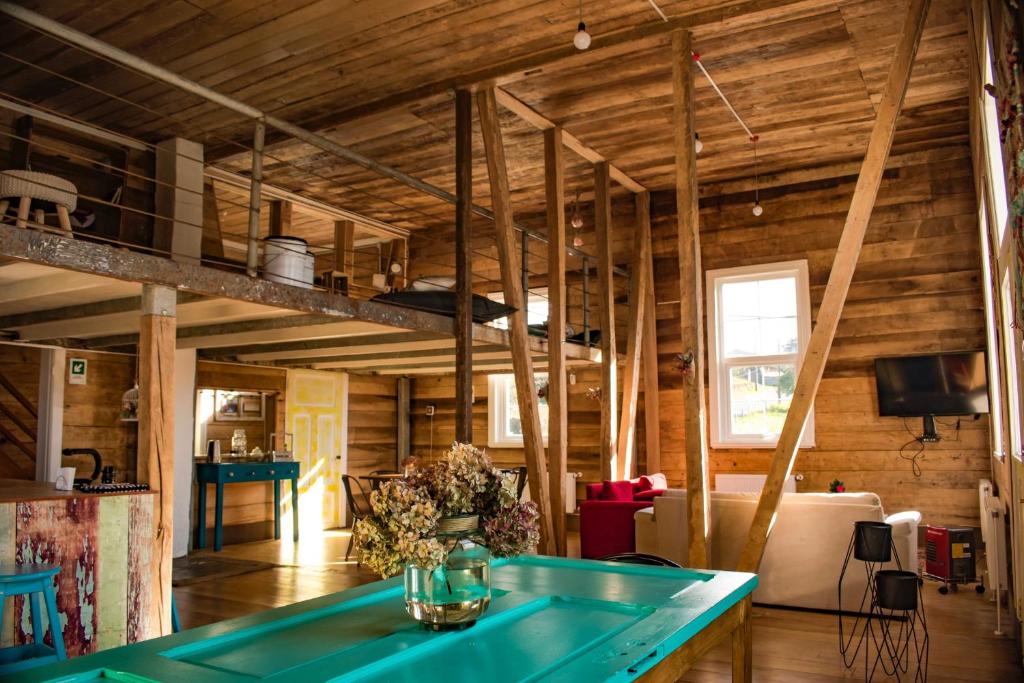 sala de estar con paredes de madera y mesa azul en Casa Apel Hostel, en Puerto Varas