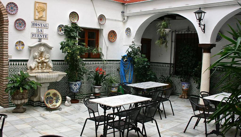 patio ze stołami, krzesłami i fontanną w obiekcie Hostal la Fuente w Kordobie