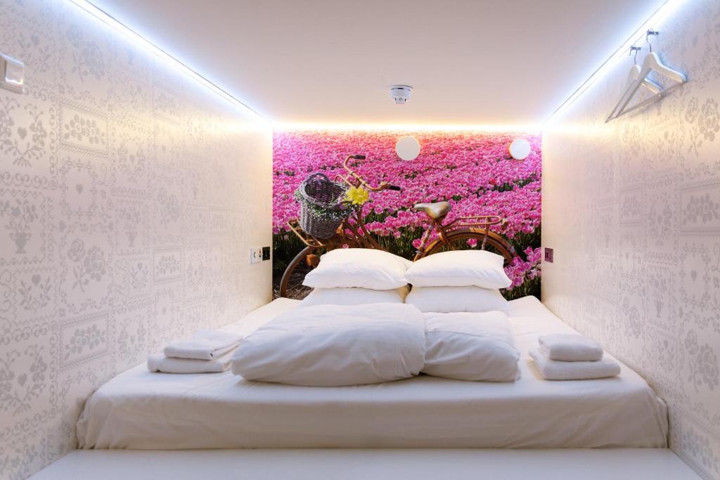 een slaapkamer met een bed met roze bloemen aan de muur bij De Bedstee Boutique Capsules in Amsterdam