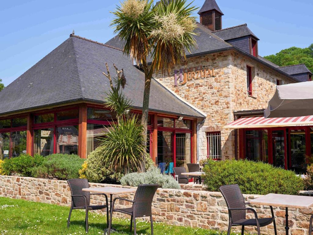 un patio con mesas y sillas frente a un edificio en Mercure Dinan Port Le Jerzual, en Dinan