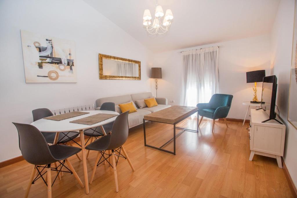 een woonkamer met een bank en een tafel en stoelen bij Apartamentos Soho Boutique Plaza Mayor Caceres in Cáceres