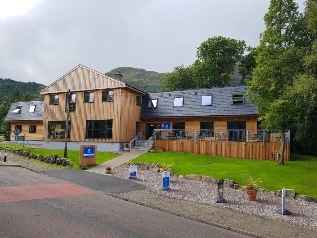 a house with a fence next to a road at Glen Nevis Youth Hostel in Fort William