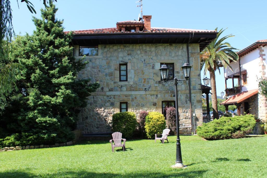 a house with two chairs and a lamp in the grass at Apartamentos Los Hidalgos in Santillana del Mar